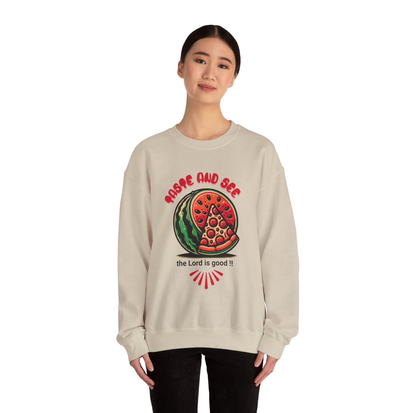 Model in beige crewneck sweatshirt with scripture quote 'Taste and See the Lord is Good' and colorful food art. Faith-inspired cozy pullover.