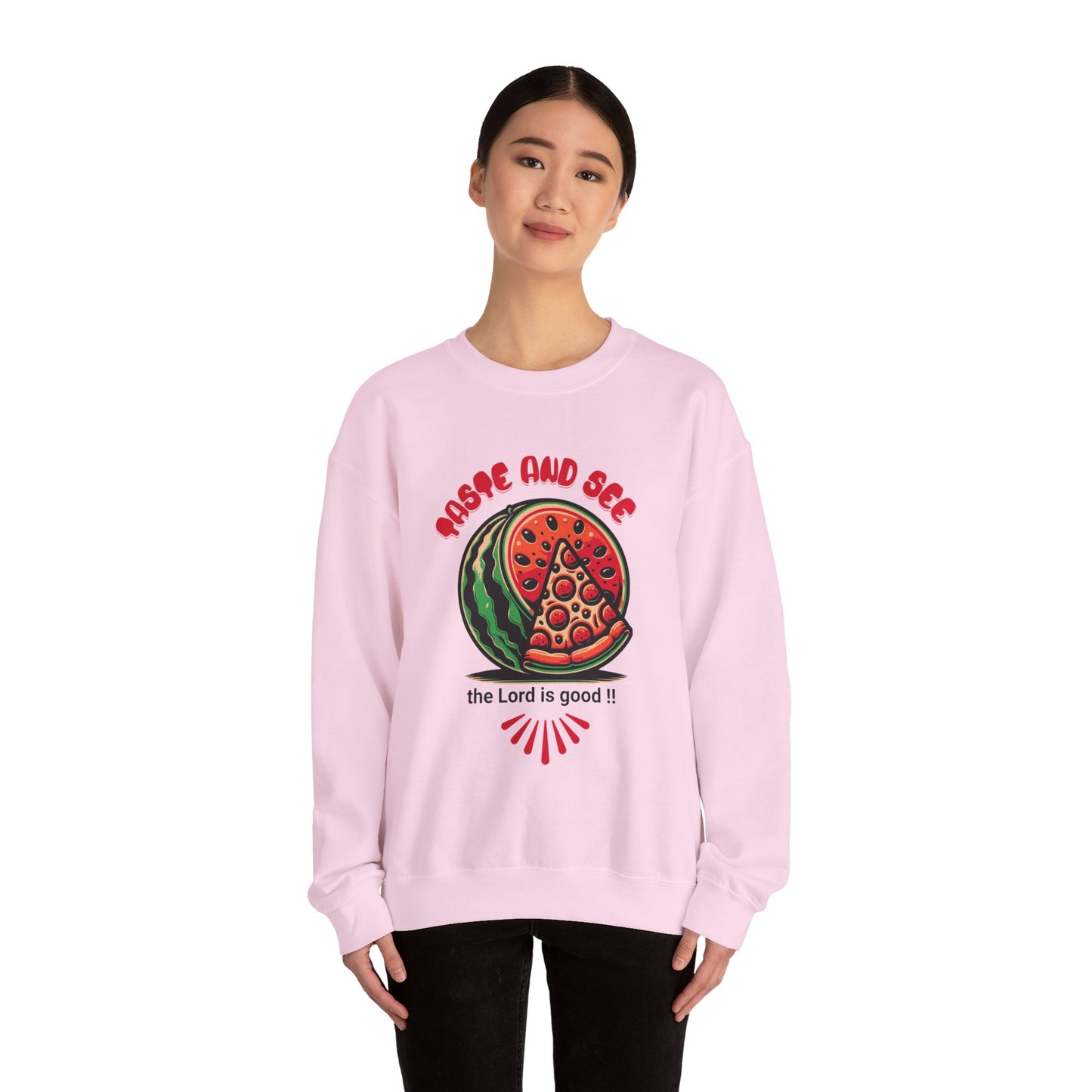 Model in pink inspirational crewneck sweatshirt with 'Taste and See the Lord is Good' message and vibrant graphic. Cozy faith-based apparel.