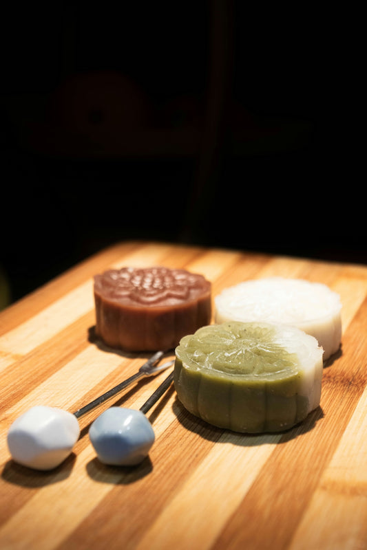 Four assorted mooncakes on a wooden board.