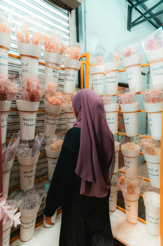 Woman in hijab browsing dried flowers at market