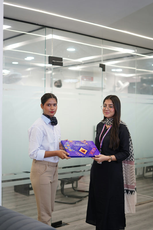 Two women holding a gift box in an office.