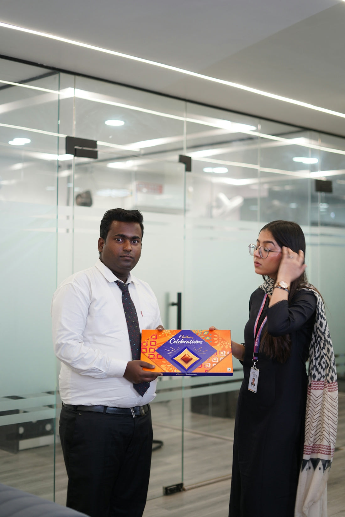 Man presents gift box to woman in office