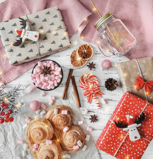 Christmas gifts, pastries, and hot chocolate ingredients arranged festively arranged.