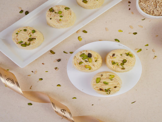 Round indian sweets topped with pistachios on plates