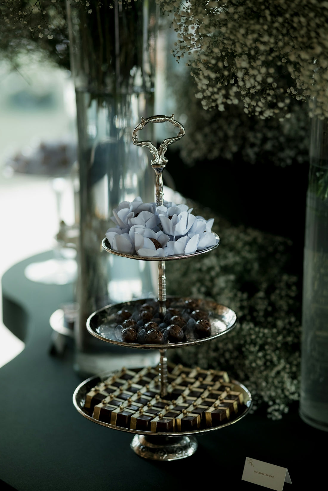 Three-tiered silver stand with assorted chocolates and candies