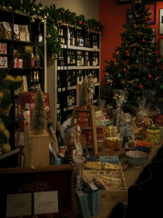 A christmas tree and festive gifts displayed in a shop.